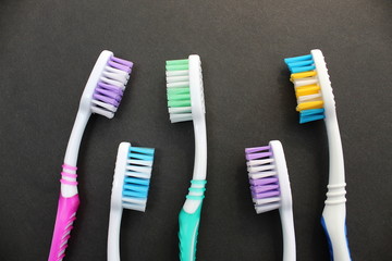 Multi-colored toothbrushes lie on a black background
