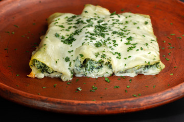 Rolls of pancakes with cottage cheese, herbs and cheese.