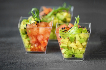 Delicious salad with avocado and tomatoes on a gray background. Close-up. Concept for food, diet and healthy food, restaurant and catering