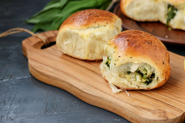 Yeast buns filled with greens and boiled eggs are located on a wooden board