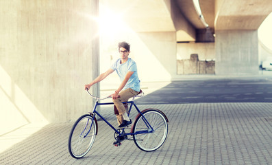 Fototapeta premium people, style, leisure and lifestyle - young hipster man riding fixed gear bike on city street