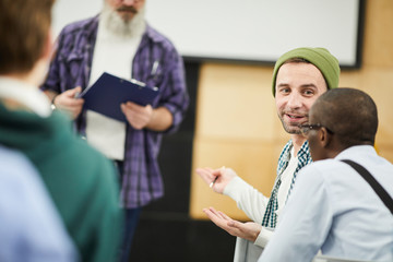Content positive students in casual clothing sitting in audience and discussing speaker while...
