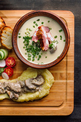 Pea soup with smoked meat in a clay plate, meat goulash with mushrooms and sauce.