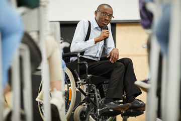 Serious confident motivational disabled mature African-American speaker in glasses sitting in...