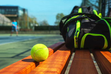 Tennis ball and sport bag on the bench on court. Concept of sport, healthy lifestyle.