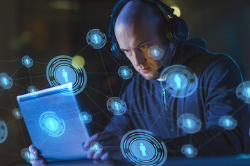 cybercrime, hacking and technology concept - male hacker with headset using laptop computer for...