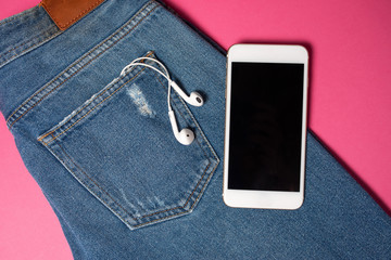 Flat background with copy space. Top view of casual woman outfit, jeans and headphones
