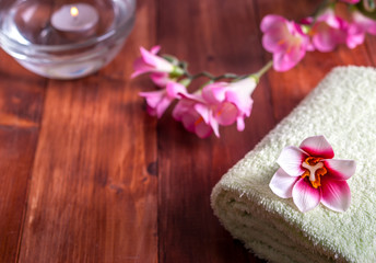 Fototapeta na wymiar Towel with flowers and a candle on a wooden background