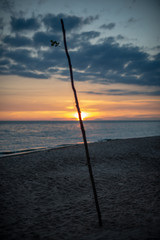 colorful sunset over calm sea beach with dark blue water and dramatic contrasty clouds