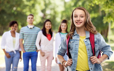 Fototapeta na wymiar education, school and people concept - happy smiling teenage student girl with bag over group of friends in summer park background