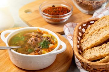 Lentil soup with chicken in a white bowl on a wooden board