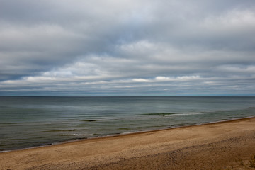 empty sea beach in autumn with lonely trees and rocks in sands