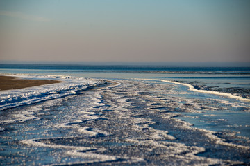 Fototapeta na wymiar frozen sea beach in winter with low snow coverage