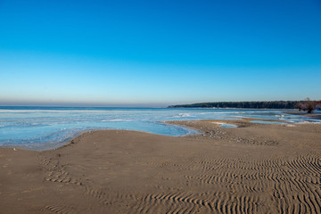 frozen sea beach in winter with low snow coverage