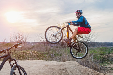 Fototapeta na wymiar A man on a mountain bike performing a dirt jump. Active lifestyle.