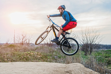 Fototapeta na wymiar Man on a mountain bike performing a dirt jump. Active lifestyle.