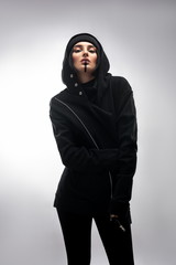 Beautiful woman in black clothes and hat over isolated gray background