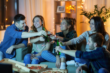 friendship, and leisure concept - happy friends with non-alcoholic drinks and pizza watching tv at home in evening