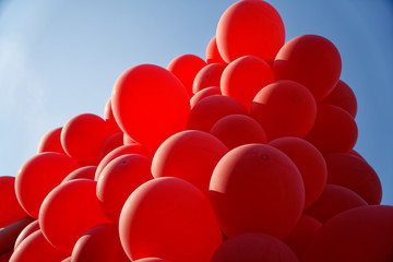 Red helium air balloon with calm blue cloudy sky on background. Peace and holiday concept. Bottom view. Copyspace for minimalistic design.