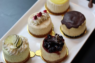 5 Cheesecakes siting on a plate with fruit topings 