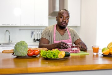 African man prepares food from fresh vegetables and meat in the kitchen