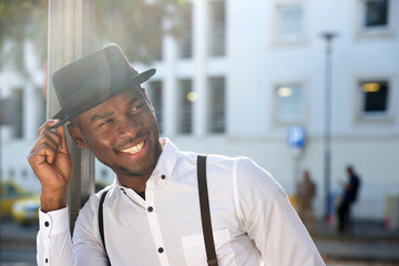 Close up handsome young african american man with suspenders and hat smiling in city