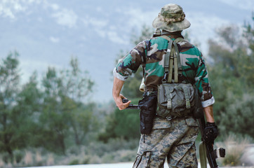 soldier  hold on rifle standing at ease forest background