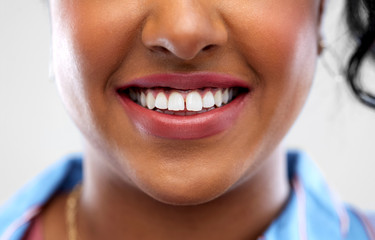 oral care, dental hygiene and people concept - close up of african american woman face with smile...