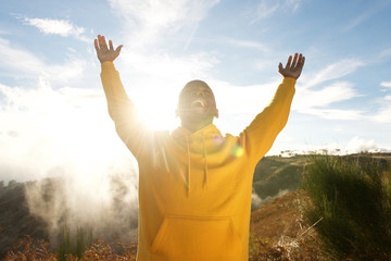 happy young african american man with arms raised in air outdoors