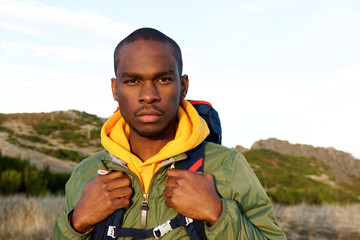 Close up handsome young african american man with backpack posing in nature