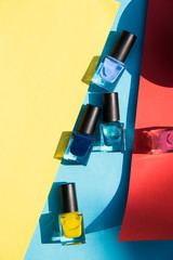 Colorful nail polish on a briht color backround with hard  shadows. 