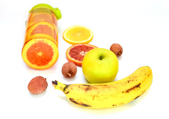 Sports bottle with lemonade from tropical fruits on a white background. Detox fruit infused water, citrus fruits .. Banana, apple, red orange, lychee. Top view, flat lay, copy space