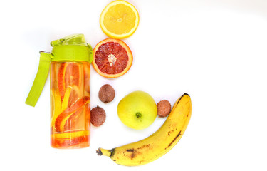 Sports bottle with lemonade from tropical fruits on a white background. Detox fruit infused water, citrus fruits .. Banana, apple, red orange, lychee. Top view, flat lay, copy space
