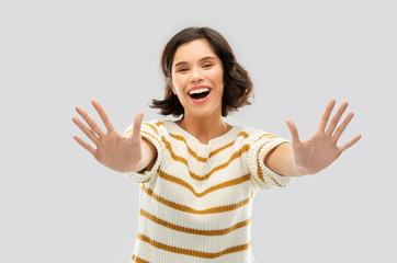 counting and people concept - happy smiling young woman in striped pullover showing ten fingers of two hands over grey background