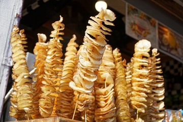 Fried potato chips on stick, Spiral potatoes fried, on wooden sticks, spiral. Selling food at the market. Unhealthy fried street food.