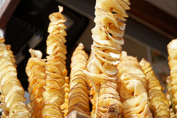 Fried potato chips on stick, Spiral potatoes fried, on wooden sticks, spiral. Selling food at the market. Unhealthy fried street food.