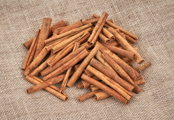 Cinnamon sticks isolated on brown burlap background. Top view.
