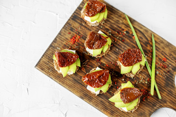 Sandwiches with cheese, avocado and dried tomatoes on the board. Concept for food, healthy food and...