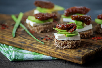 Hearty sandwiches with avocado, cheese and dried tomatoes. Close-up. Concept for food, healthy food and vegetarians.