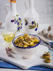 Grilled olives with garlic, olive oil and spices on white rustic table