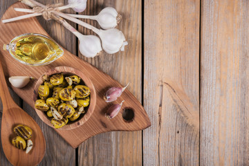 Grilled olives with garlic, olive oil and spices on rustic wooden table