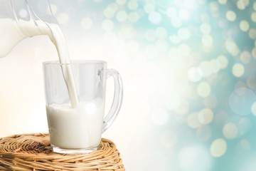 Glass of milk and jug on wooden background