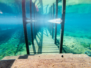 Beautiful image of wood stairs going down in the turquoise water