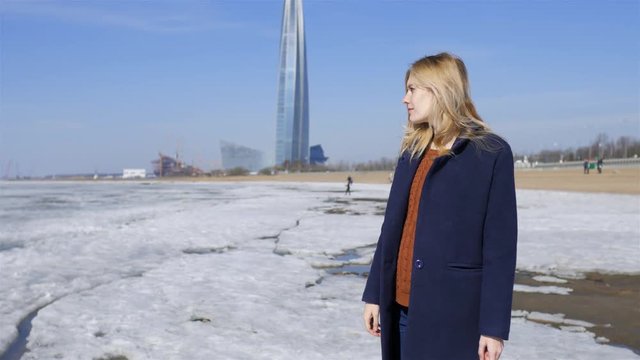 stylish woman standing on a frozen beach on the background of a skyscraper