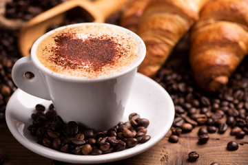 Cup of coffee surrounded by coffee beans