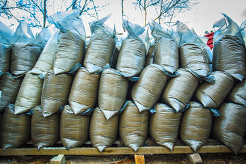 Plastic bags with sand and earth stand in rows on top of each other, building materials.