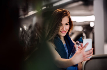 A portrait of young girl or woman with smartphone in a gym, taking selfie.