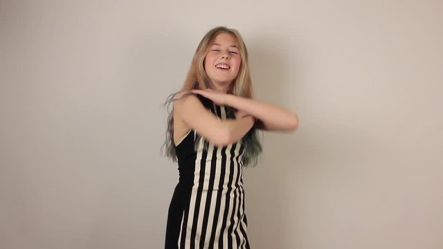 Cute girl is dancing macarena dance on gray background.