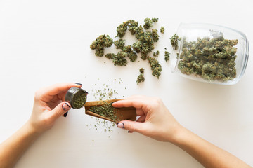 Cannabis use concept. Woman rolling a marijuana blunt on white background. Close up of marijuana...