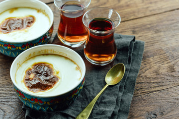 Turkish rice pudding, black tea, wooden table, close-up